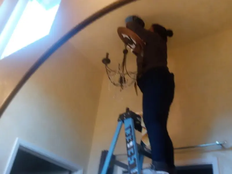 Electrician installing a chandelier in a Anthony residence